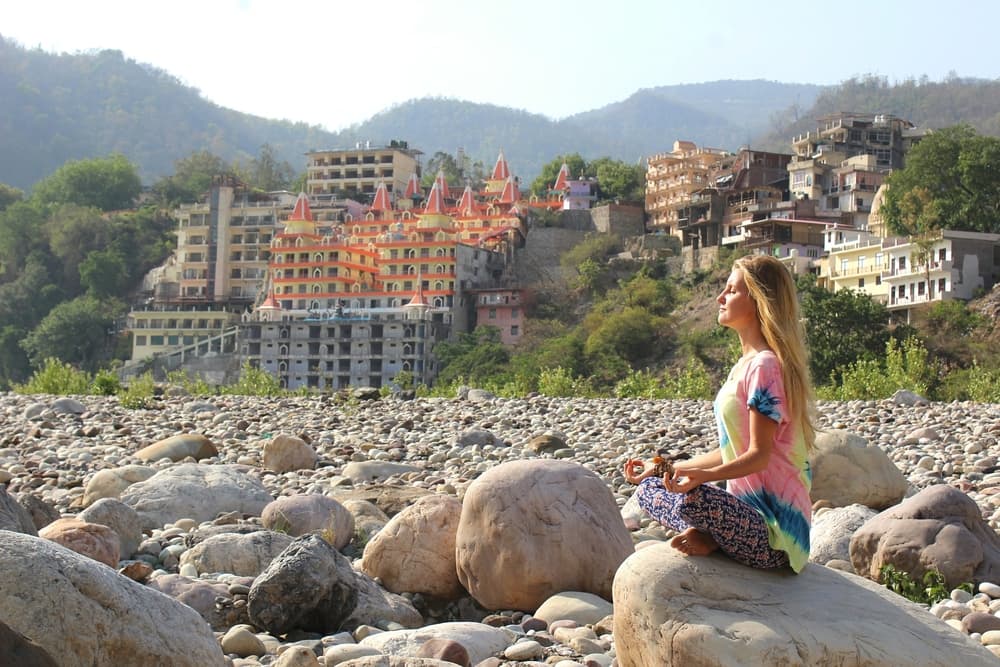 Meditação serena às margens do rio em Rishikesh com vista para templos e montanhas