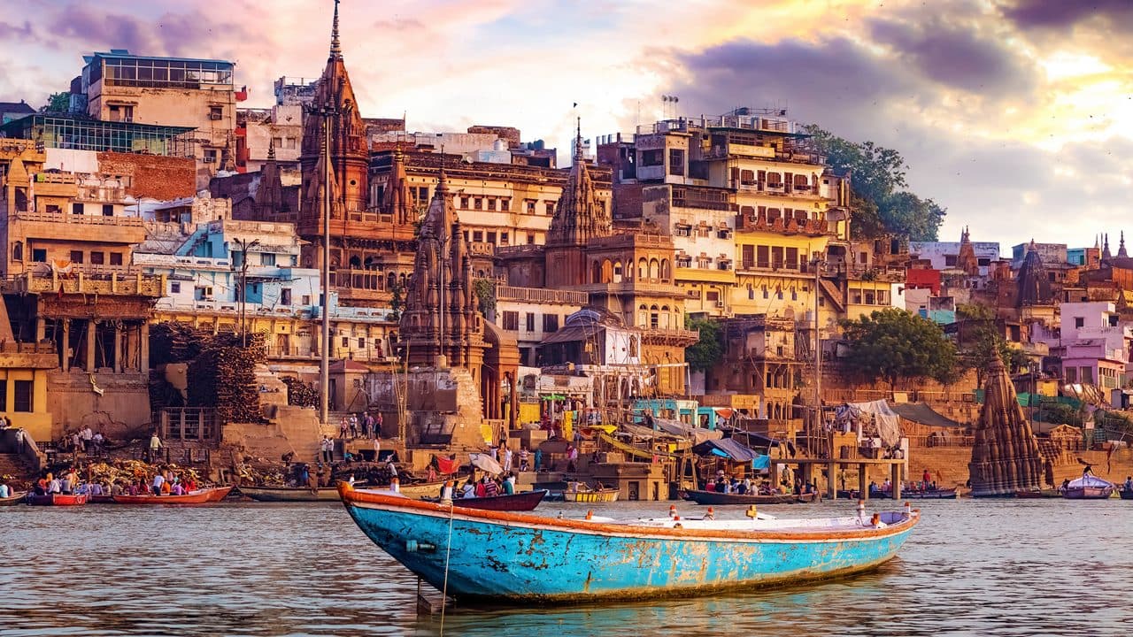 Vista dos ghats sagrados de Varanasi com barco tradicional no Rio Ganges