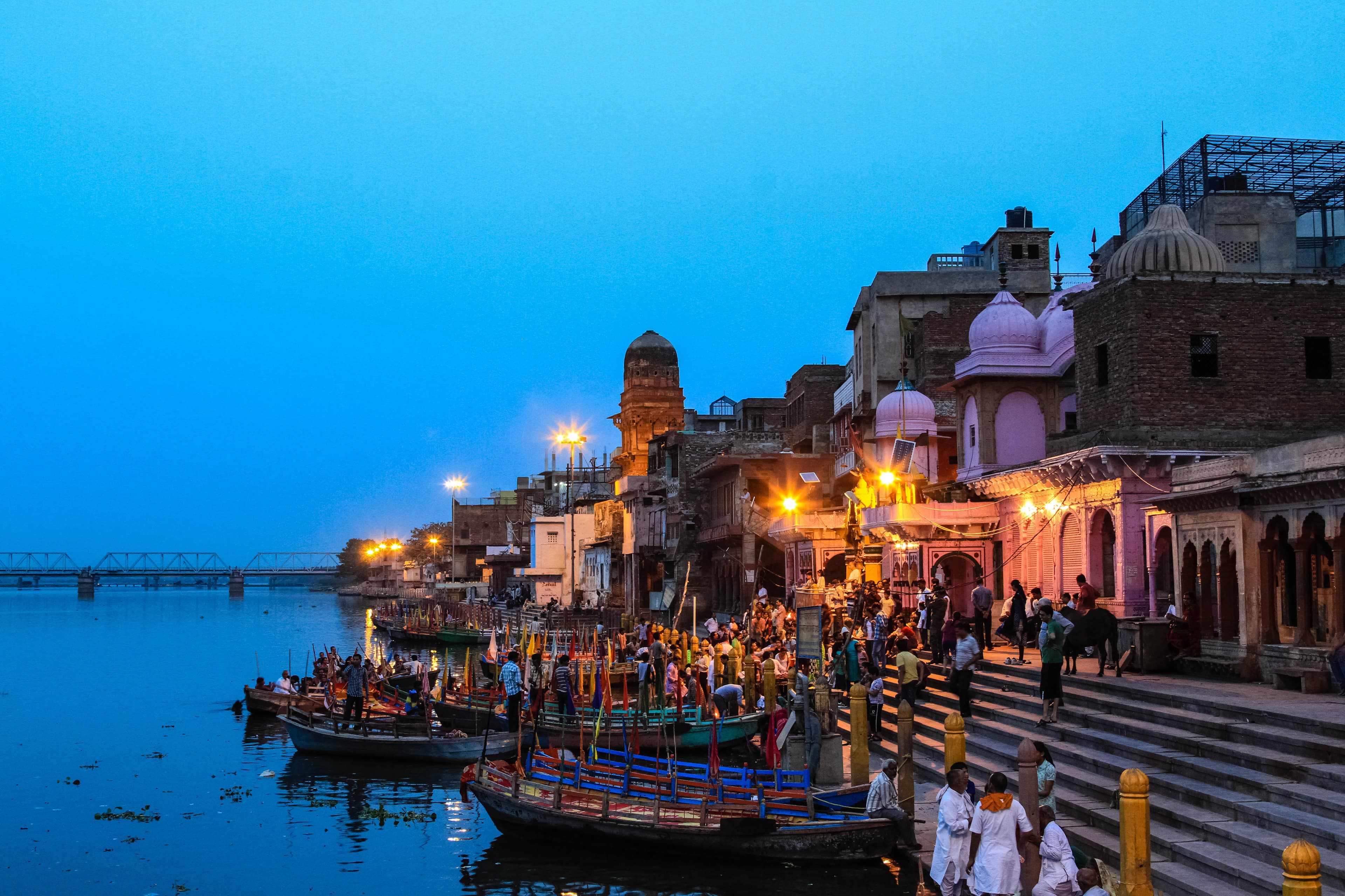 Vishram Ghat during evening twilight with traditional boats, pilgrims, and sacred architecture illuminated by warm lights